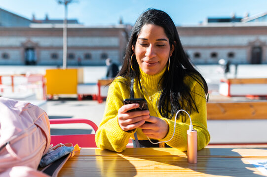 Brown skinned woman browsing smartphone on coffe shop