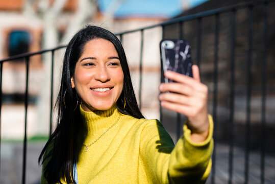 Happy woman taking selfie in city 