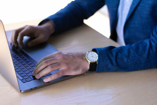 Working on keyboard laptop computer successful businessman in a jacket sitting at a table - Powered by Adobe