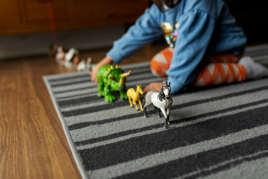 little girl playing with horses and dinosaurs