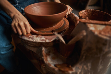Fototapeta na wymiar Unrecognized female artisan making ceramic bowl in pottery workshop