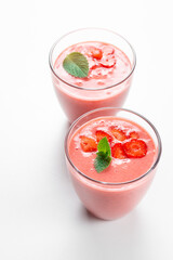 Fresh strawberry milkshake decorated with berries and mint on a white isolated background, the concept of a healthy breakfast, diet and good nutrition.