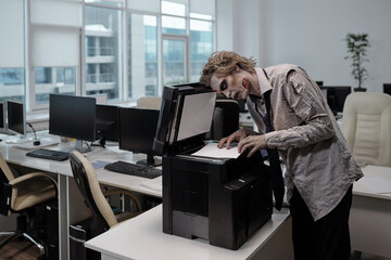 Zombie businessman standing by xerox machine and copying documents in office