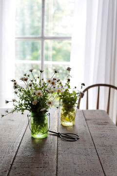 Glass jars of herbs and flowers on kitchen table