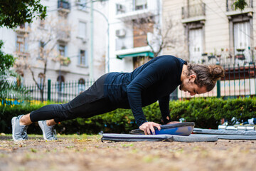 young Brazilian long-haired man doing push-up with a half ball, bosu ball, training in an outdoor city park - Powered by Adobe