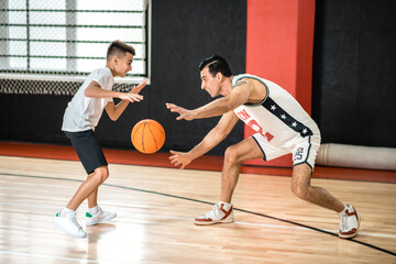 Dark-haired man training a teen in the gym