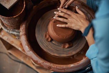 Unrecognized female artisan modeling ceramic and pottery tableware in modern cozy workshop