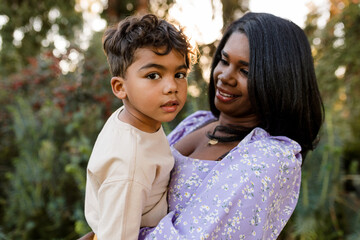Young Boy Looks at Camera While His Mother Holds Him in Her Arms