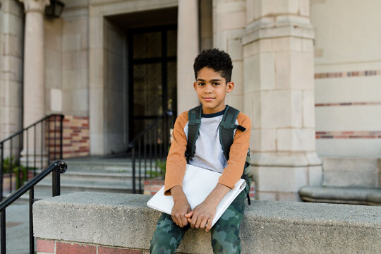 Young Boy Holds His School Books While Sitting on the Steps
