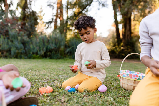 Little Boy Sits on the Grass and Plays With Plastic Easter eggs in the Park