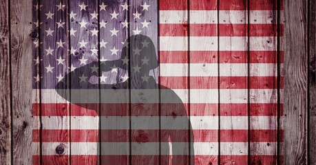 Composition of silhouette of saluting soldier against american flag painted on old wooden planks