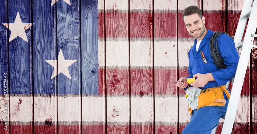 Poster Composition of smiling male electrician on ladder over american flag painted on wooden boards