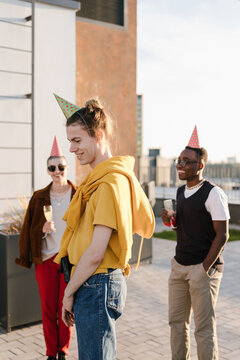Cheerful diverse friends celebrating birthday on terrace