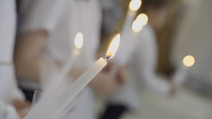 lighted candles in the hands of children who receive the first communion. selective focus and blur