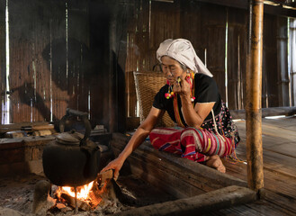 A portrait of karen tribe woman using cigarette to smoke, boiling water by using traditional kettle...
