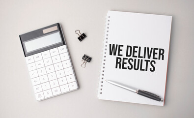 The word We Deliver Results is written on a white background next to a pen ,calculator and reports. Business concept