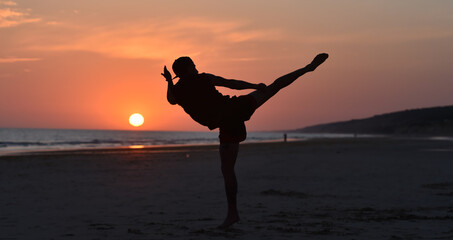 A fighter training on the beach at sunset