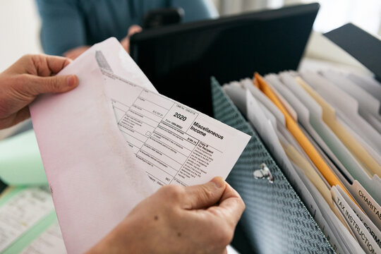 Taxes: Woman Opens Envelope With 1099 Miscellaneous Income Form