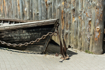 Detail of an old wooden boat's bow by the river with hanging chain and anchor