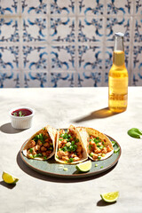 Tacos with meat and herbs, sauce and lime. National Mexican street food. On a light background.
