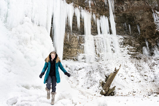 Teen Girl Hiking and Exploring a Frozen Waterfall in Winter Land