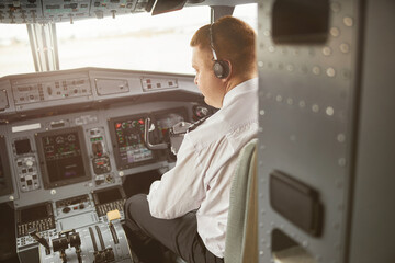 Male pilot in cockpit of passenger airplane jet