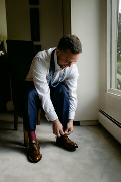 groom tying his shoes before the ceremony