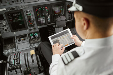 Pilot use digital tablet in passenger airplane jet - obrazy, fototapety, plakaty