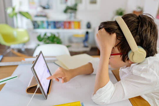 Pensive Pre-teen using am iPad while designing a project sitting at table