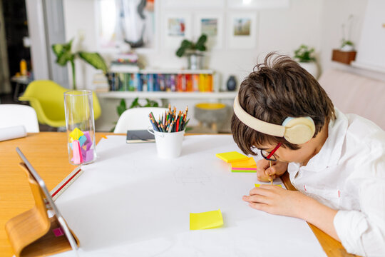 Side view Teen Boy wearing white shirt writing on a stick note pad a gratitude