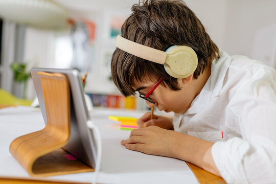 Side view Teen Boy wearing white shirt writing on a stick note pad a gratitude