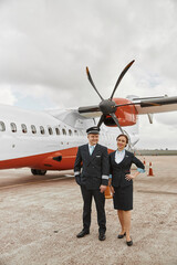 Pilot and stewardess on runway near airplane jet