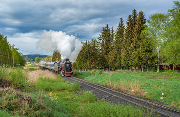 Vintage black steam locomotive train with wagons rush railway.