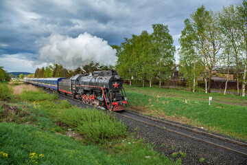 Vintage black steam locomotive train with wagons rush railway.
