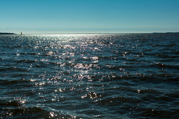 Sun glare in waves of sea water on a tropical beach in summer in nature close-up. Beautiful texture of water waves.Sea wave and sand seashore. Golden sun light over the sea ocean waves