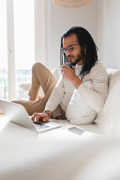 Handsome guy lying on the sofa while using his laptop