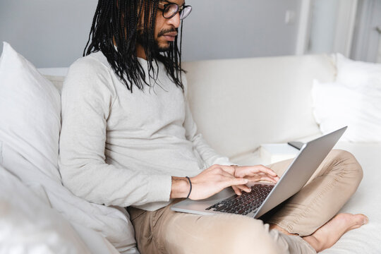 Handsome man using his laptop on sofa at home