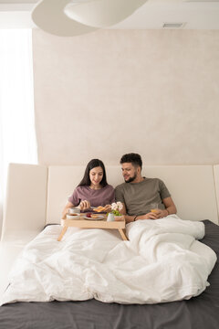 Young couple having breakfast in bed after sleep