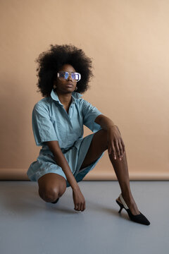 Black woman in blue dress and glasses