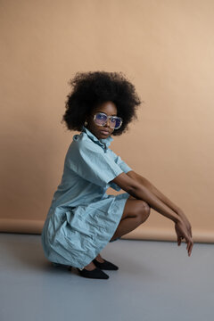 Black woman in blue dress and glasses