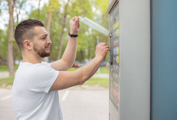 Man inserting coin money in car washing machine.