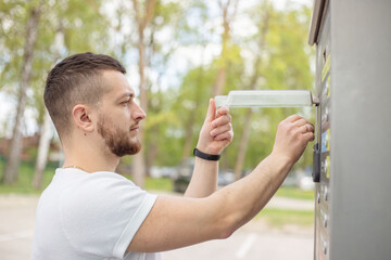 Man inserting coin money in car washing machine.