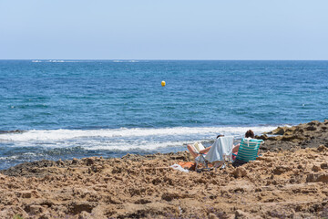 Rocky beach where two people sunbathe in hammocks, Javea, Alicante, Spainn