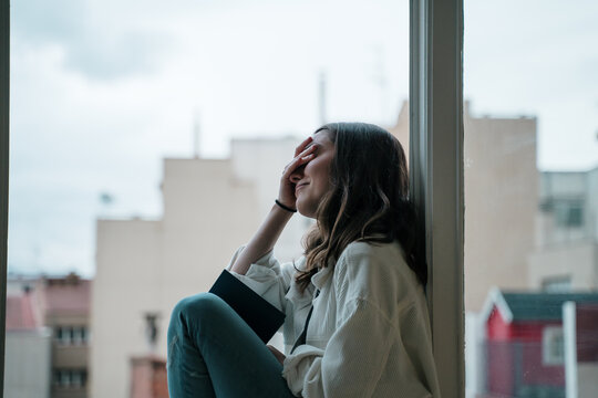 Young woman sitting on a window sill