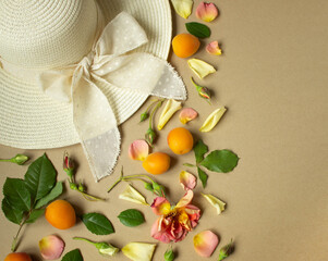 beige hat, rose buds, flower petals, leaves, apricots lie on a wooden table with a place for text, top view