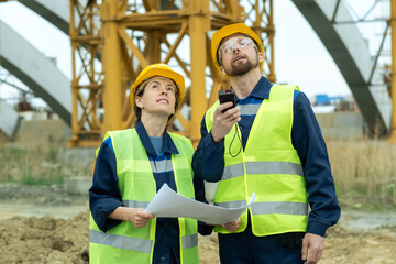 Two young builders looking upwards during work on construction site