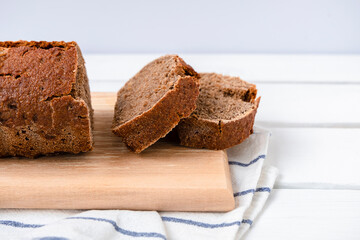 Sourdough rye bread sliced on a cutting board on white wooden table with copy space
