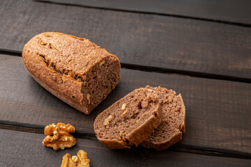Slices of walnut sourdough bread on dark wooden background with copy space