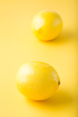 Two ripe whole lemons on a yellow background. Detox fruit diet, body detoxification. Vertical view