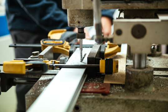 Master using drilling machine in workshop